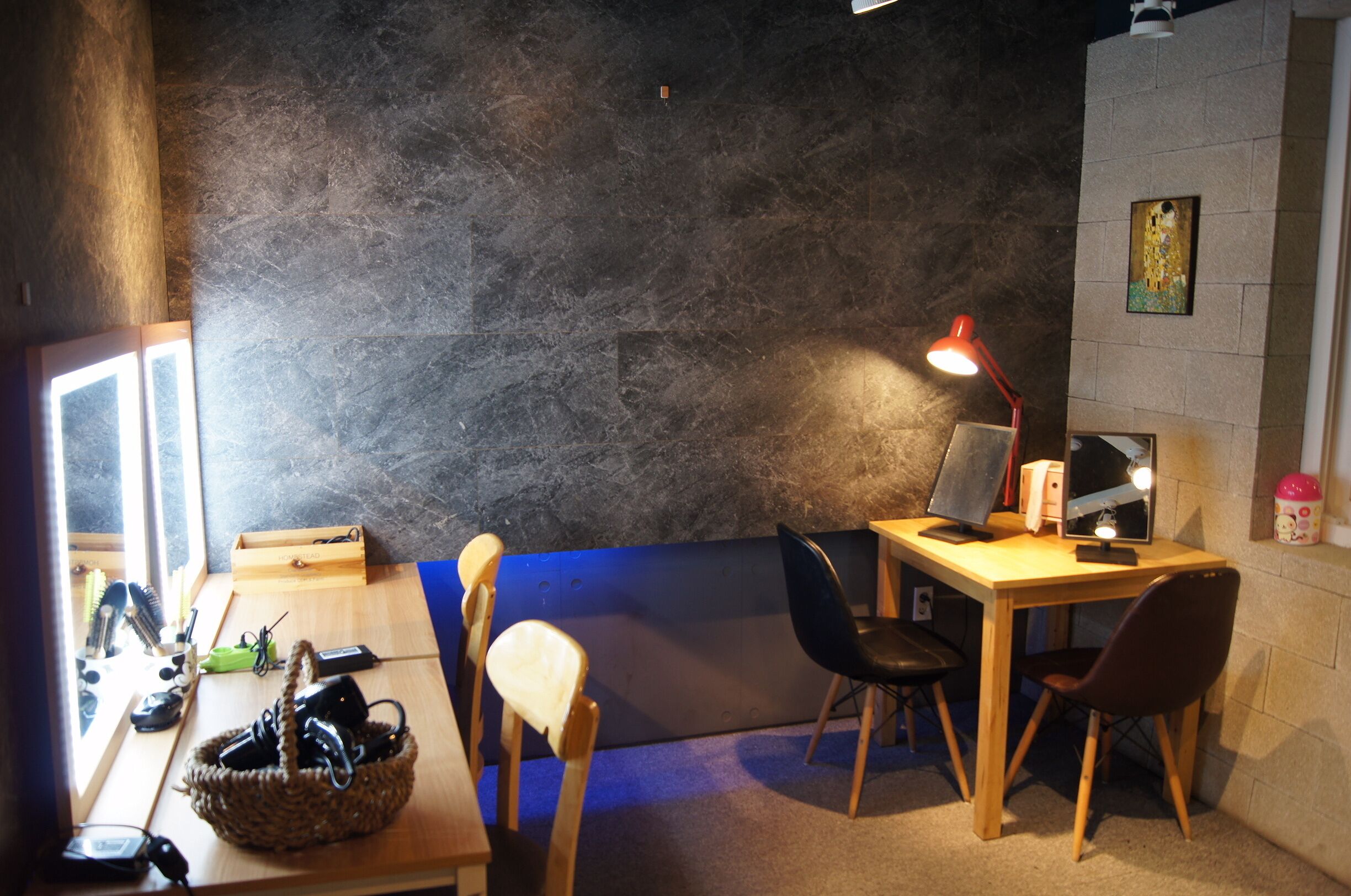 A room with a wooden desk, two chairs, a laptop, a lamp, and a window.