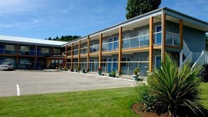 A multi-story hotel with a modern design, featuring a central atrium with glass railings and a parking lot in front. - Island View Lodge (Powell River)