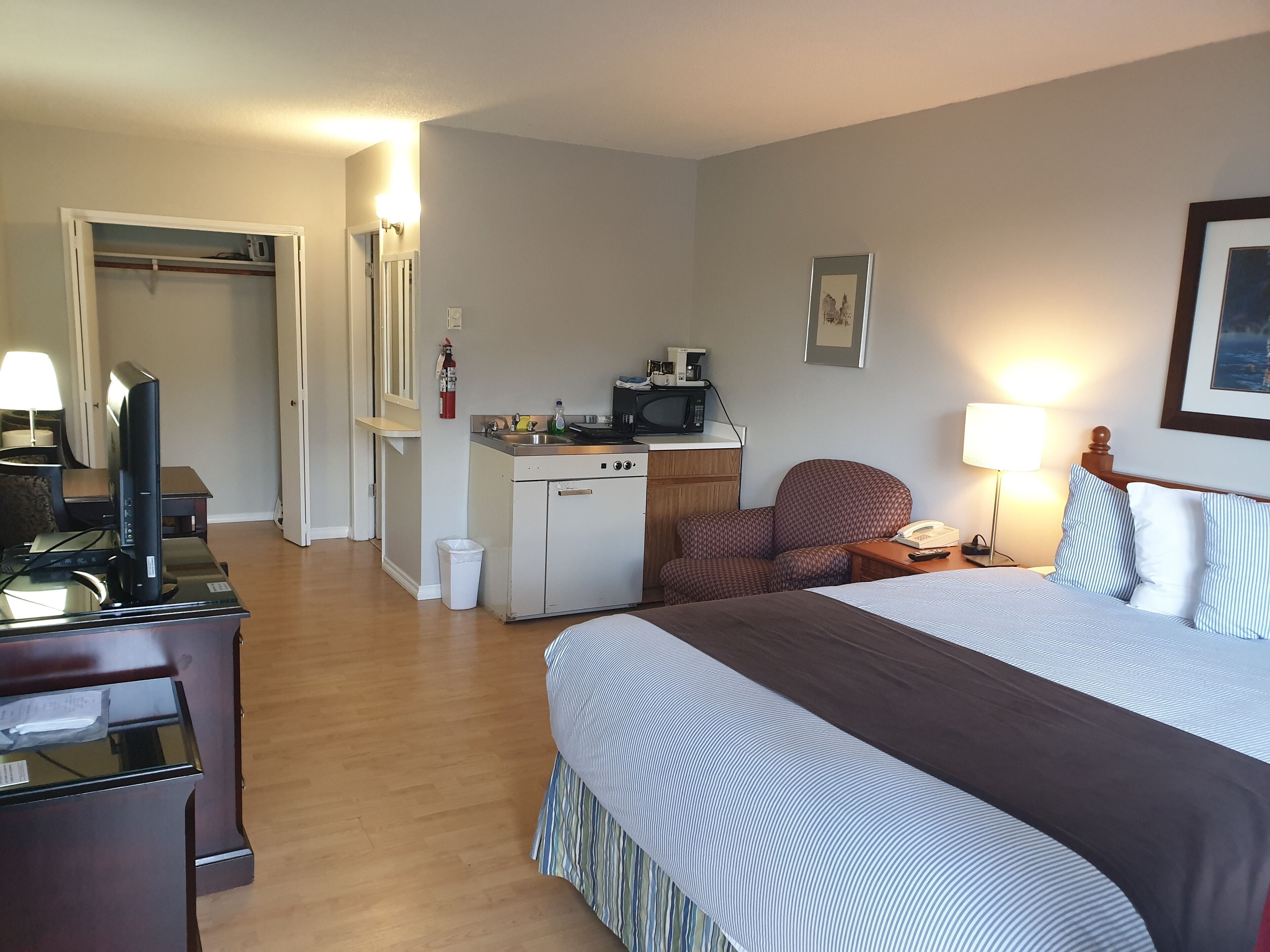Habitación de hotel con cama, escritorio, kitchenette y una silla.