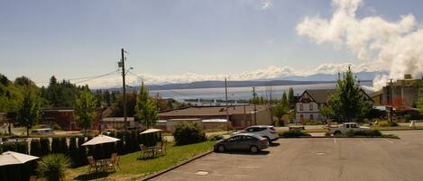 A parking lot with cars, a building with a sign, and a view of mountains and water.