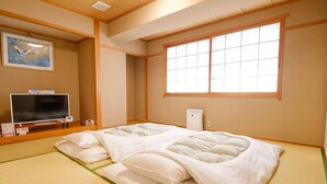 A traditional Japanese room with tatami flooring, a futon bed, a television, and a window with shoji screens. - Tennen Onsen Matsuyama New Grand Hotel (Matsuyama)