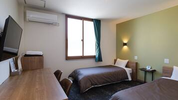 Et hotelværelse med to senge, et skrivebord, et fjernsyn og et vindue med gardiner.