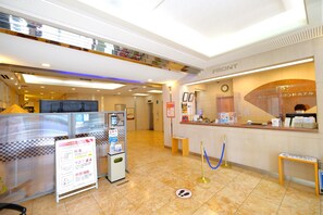A hotel reception area with a check-in counter, a self-service kiosk, and a sign with information. - Tennen Onsen Matsuyama New Grand Hotel (Matsuyama)