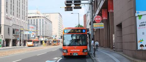 A city street with a bus, buildings, and a pedestrian crossing.
