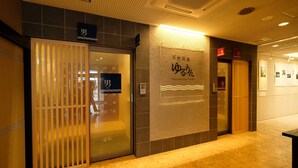 A hotel corridor with men's and women's restrooms, a sign for a natural hot spring, and a tiled floor. - Tennen Onsen Matsuyama New Grand Hotel (Matsuyama)