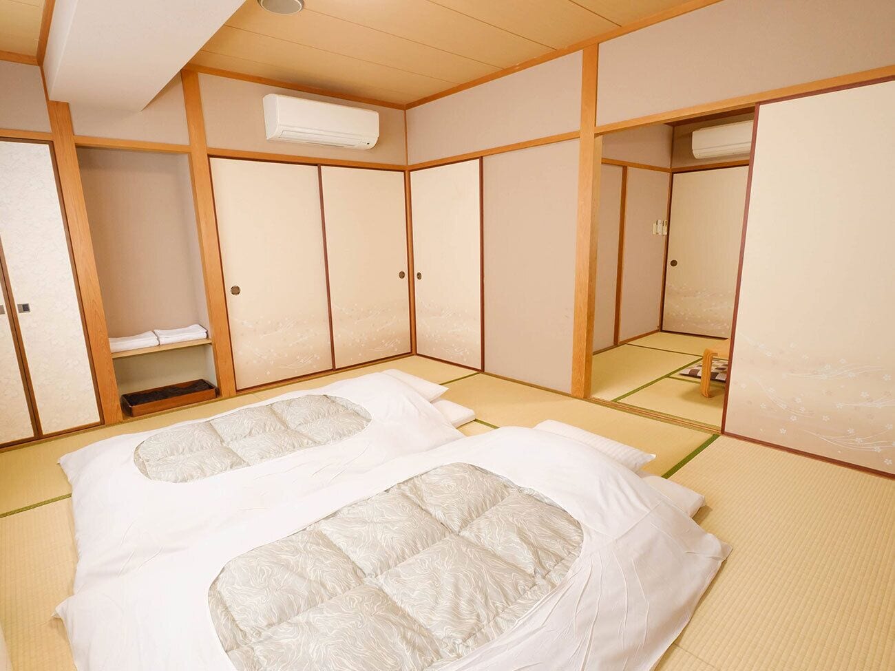 A traditional Japanese-style room with tatami flooring, a futon bed, and sliding doors.