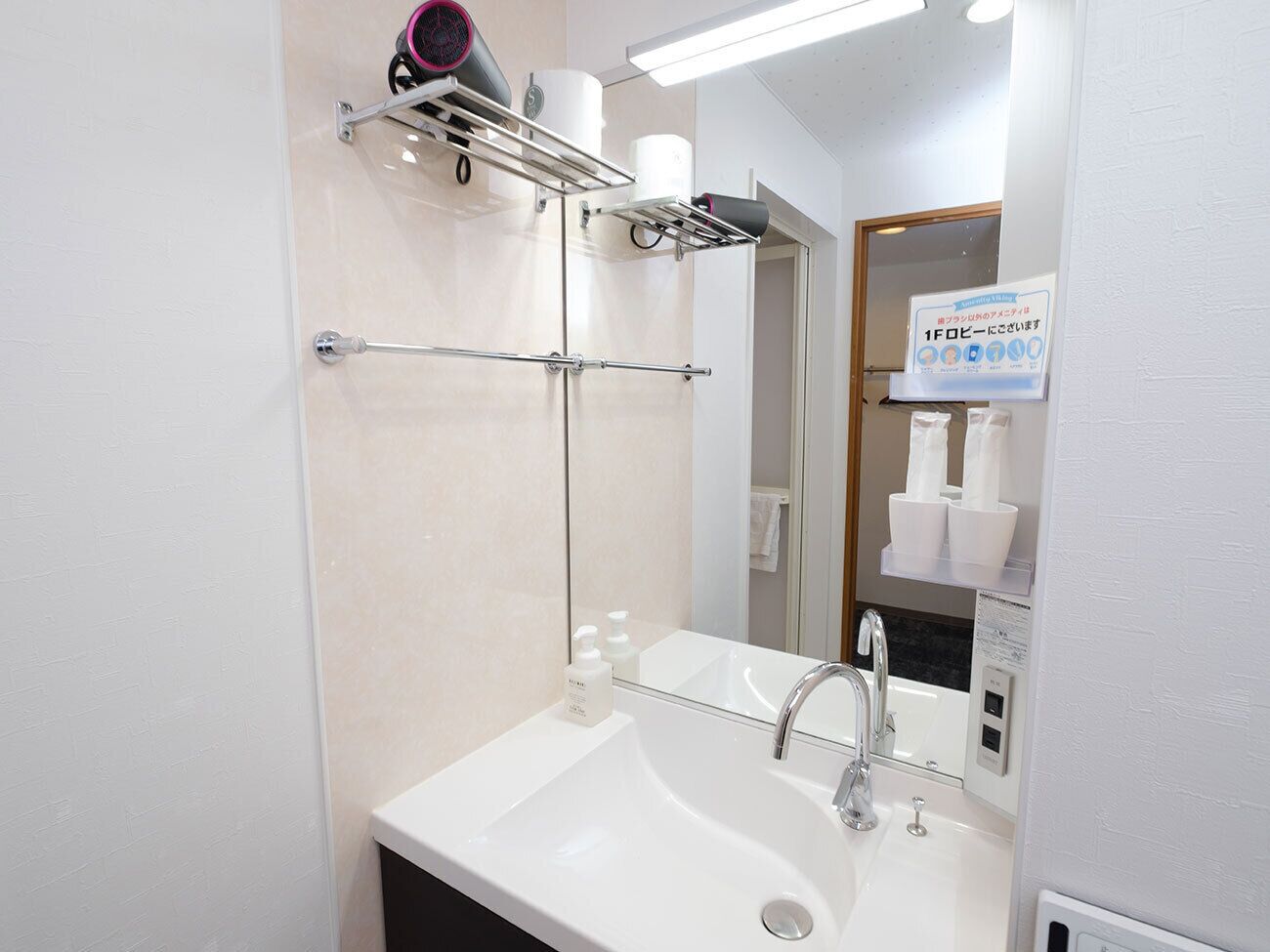 A modern bathroom with a white sink, a mirror, a towel rack, and a hairdryer.