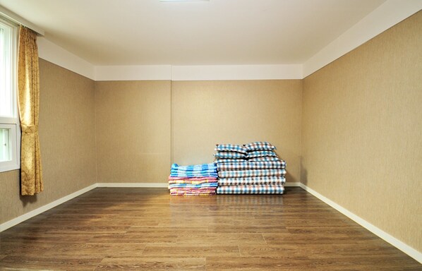 A room with beige walls, a wooden floor, and a window with curtains. - Chambord Hotel (Yeosu)