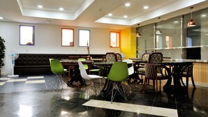 Un espace repas moderne comprenant un assortiment de chaises et de tables, un canapé et un ventilateur.