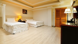 Une chambre d’hôtel avec deux lits, une table de chevet avec une lampe, une armoire en bois et un miroir.