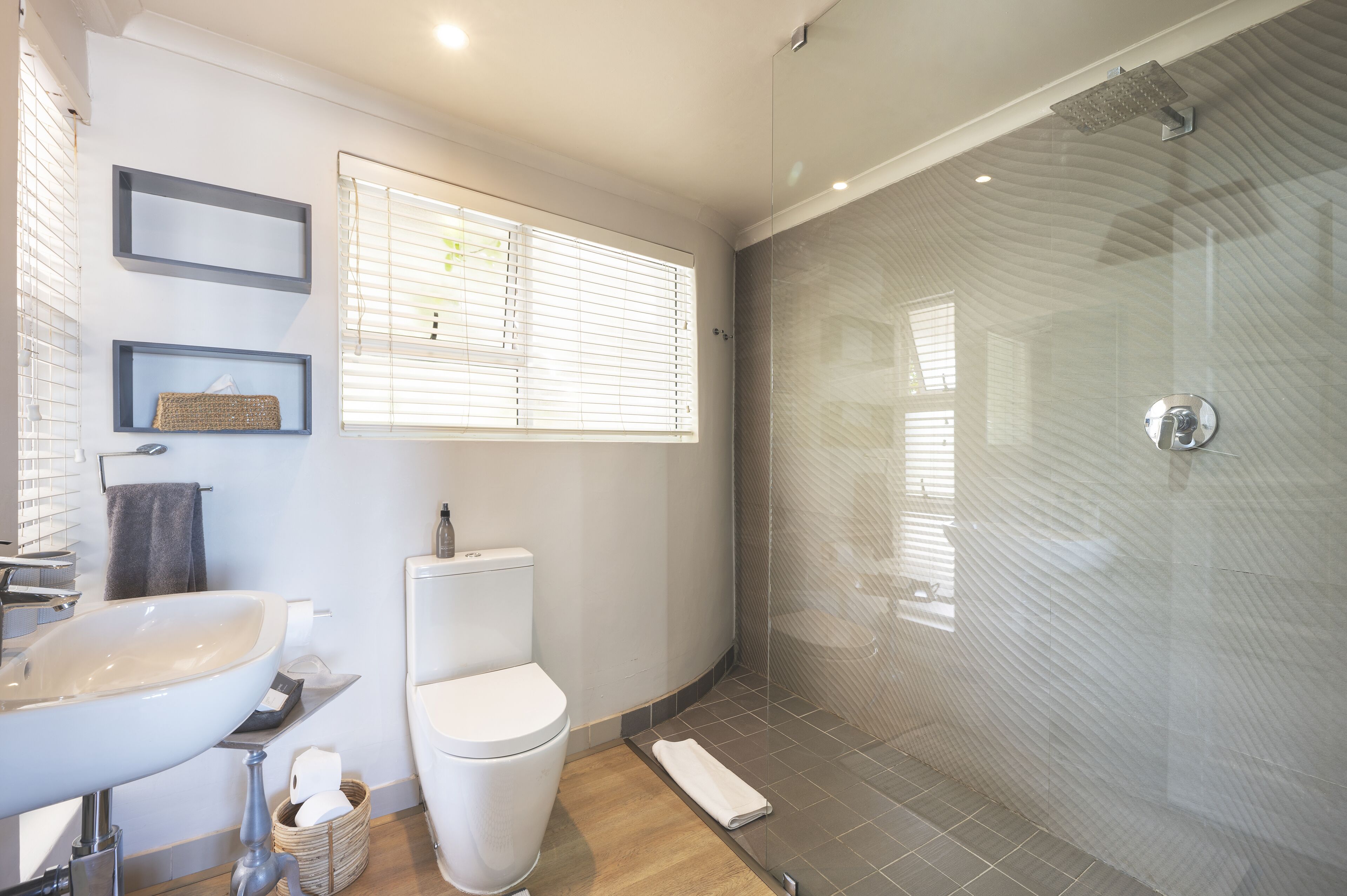 Une salle de bain moderne avec une douche à parois de verre, un lavabo blanc et des toilettes.