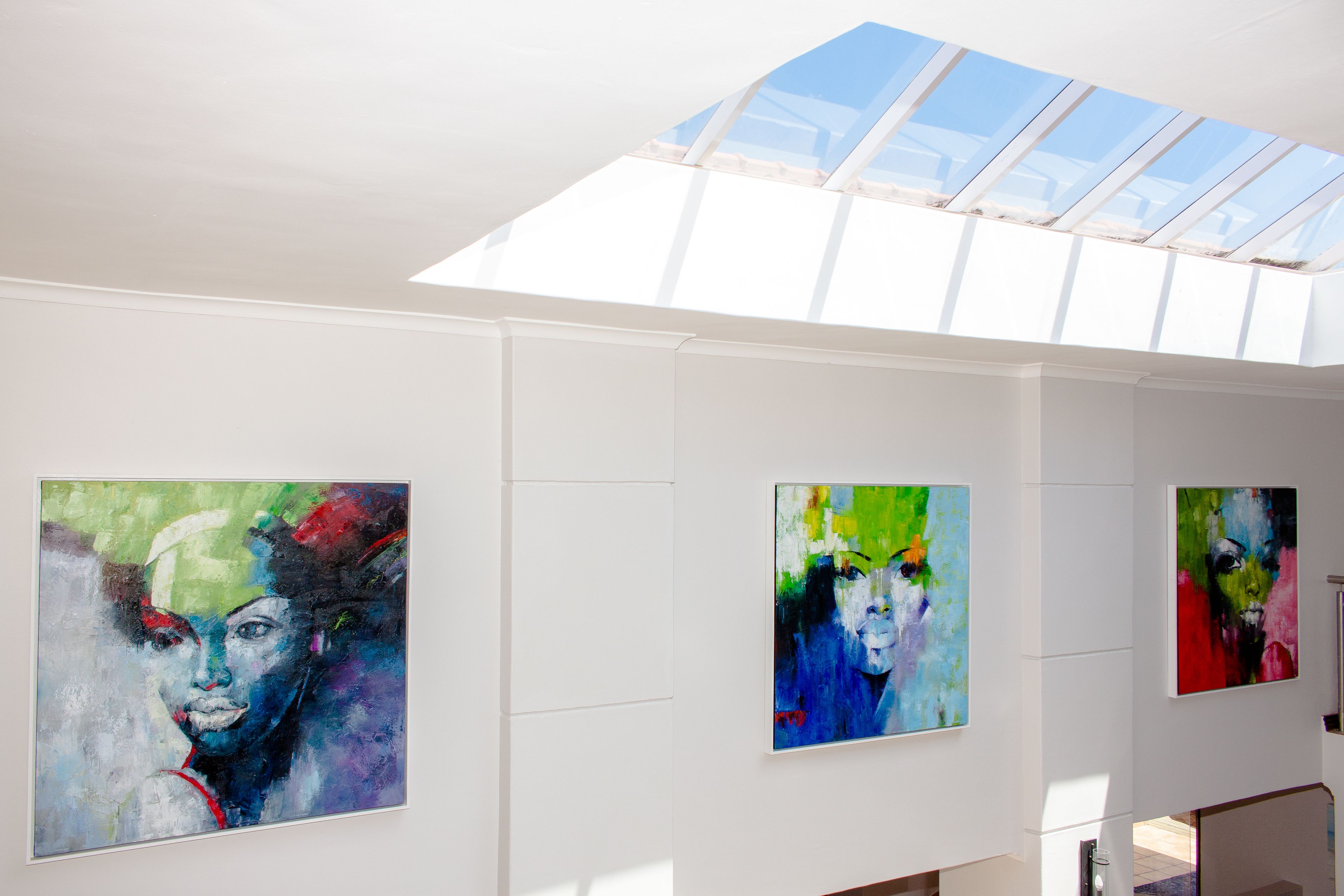 Una galería con pinturas abstractas en las paredes y un tragaluz.