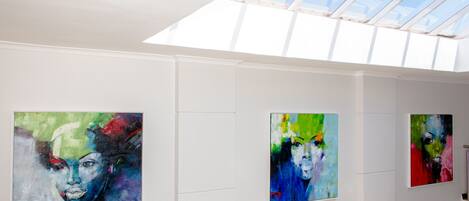 Una galería con pinturas abstractas en las paredes y un tragaluz.