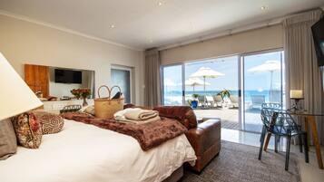 Une chambre d’hôtel avec un grand lit, un canapé, une télévision et un balcon donnant sur la mer.