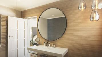 A modern bathroom with a large round mirror, a white sink, and two pendant lights.