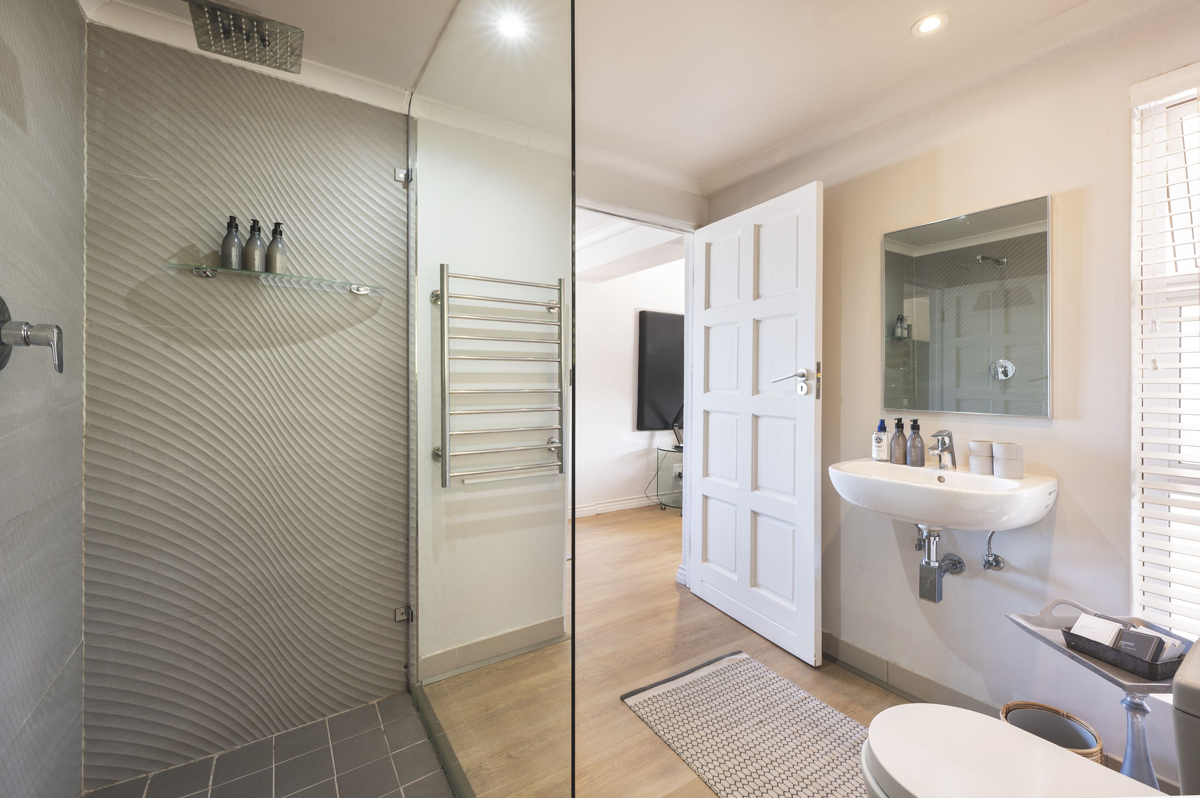 A modern bathroom with a glass shower enclosure, a white sink, and a toilet.