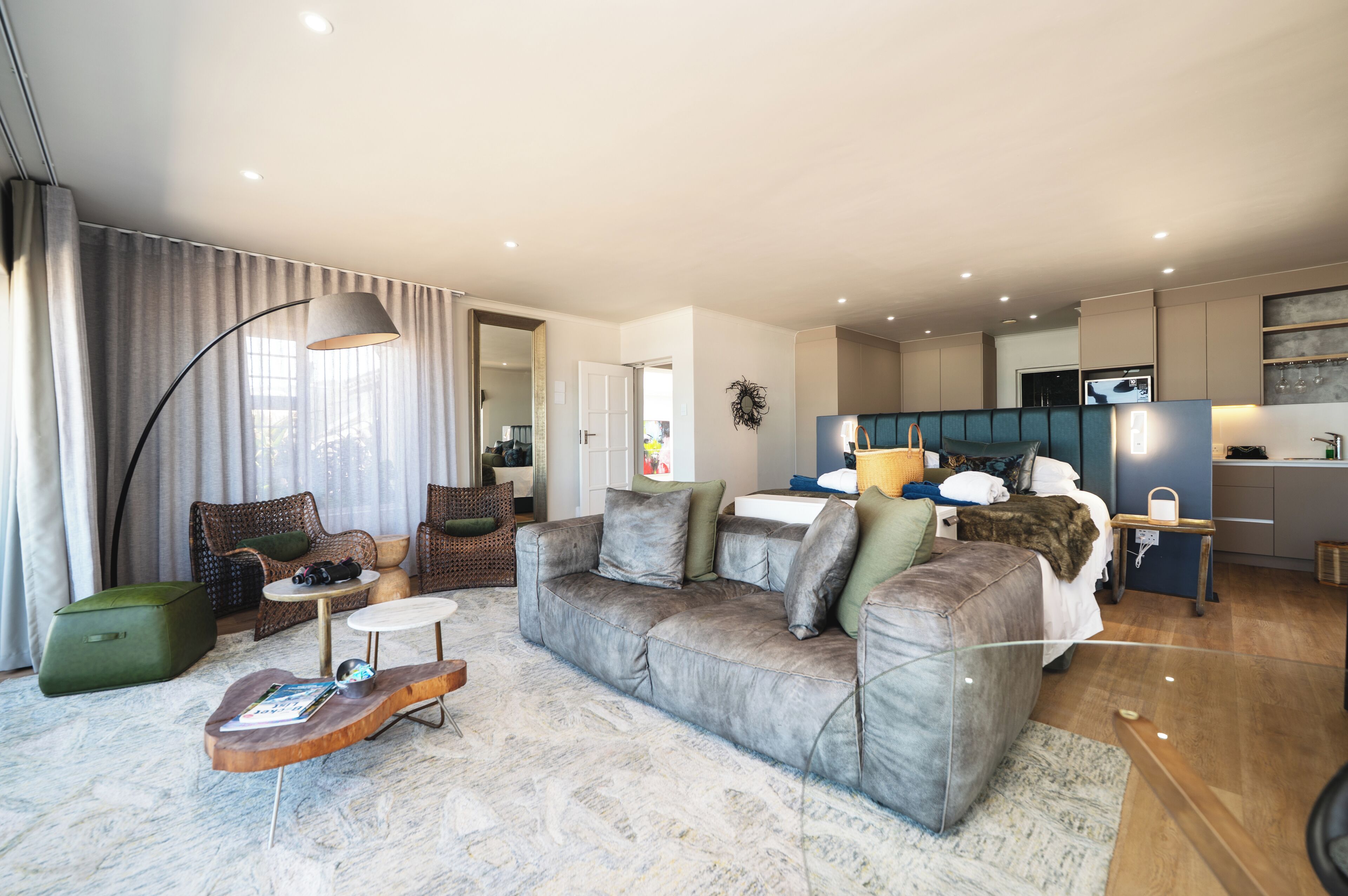 A modern living room with a grey sofa, a coffee table, and a green ottoman.