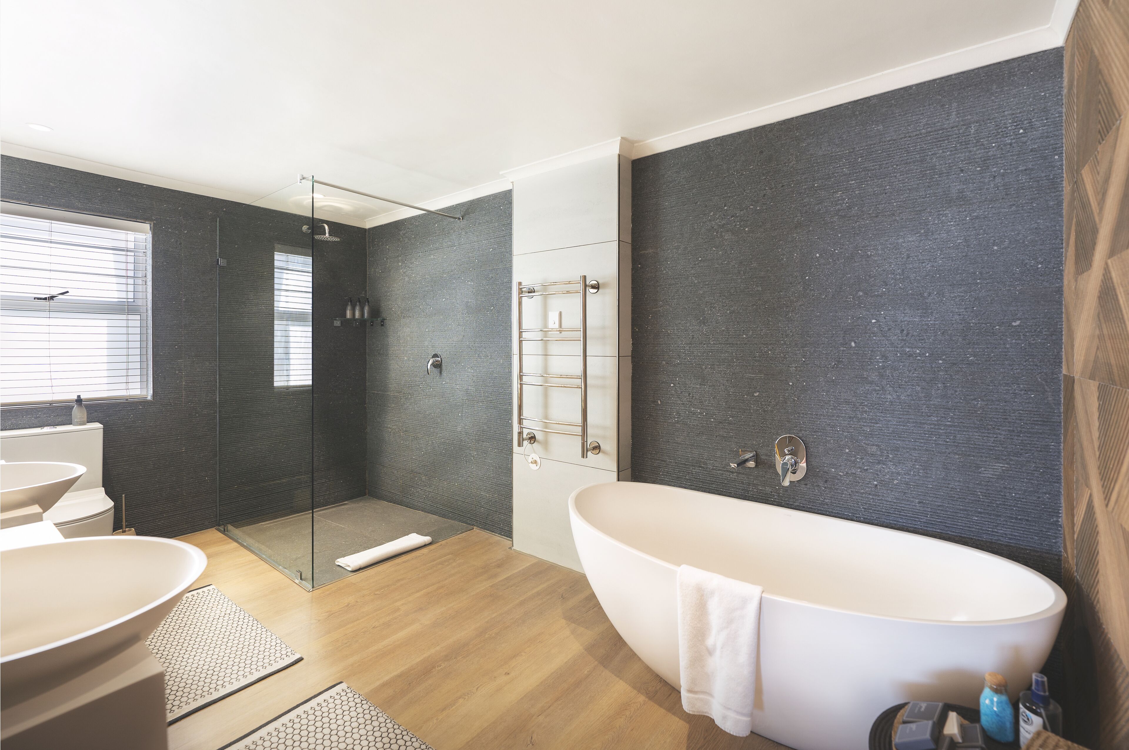 Un baño moderno con una bañera independiente, ducha con mampara de vidrio y un amplio ventanal.