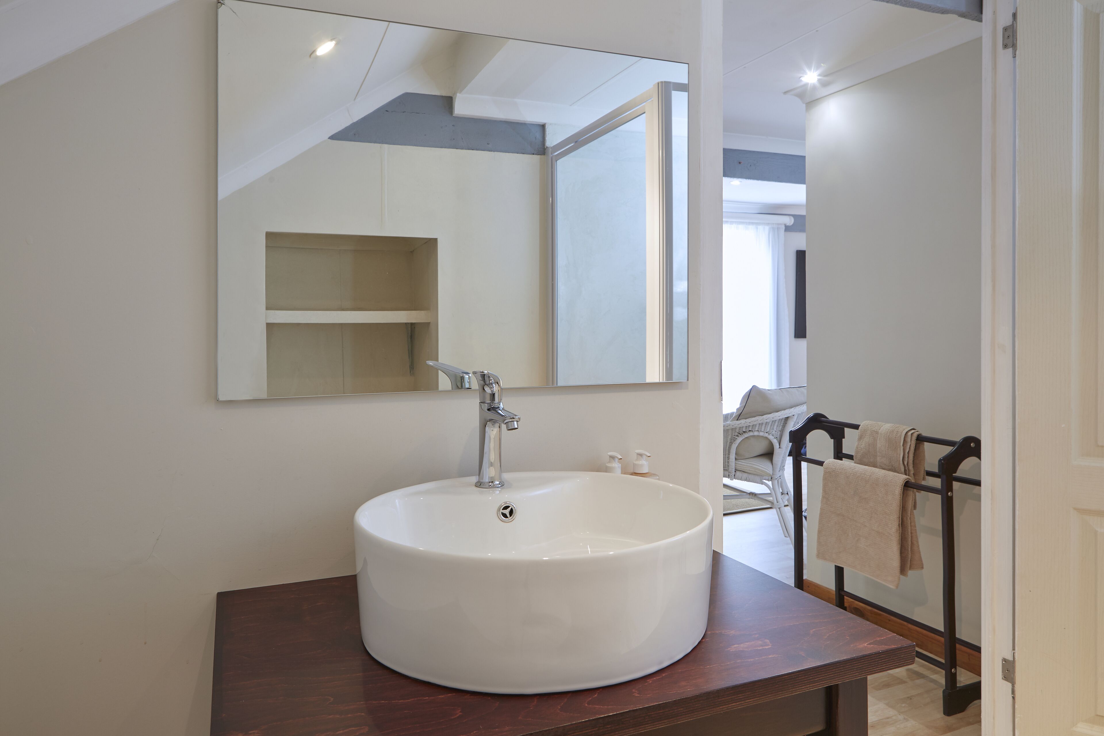 A bathroom with a large white sink, a mirror, and a towel rack.
