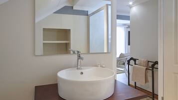 A bathroom with a large white sink, a mirror, and a towel rack.