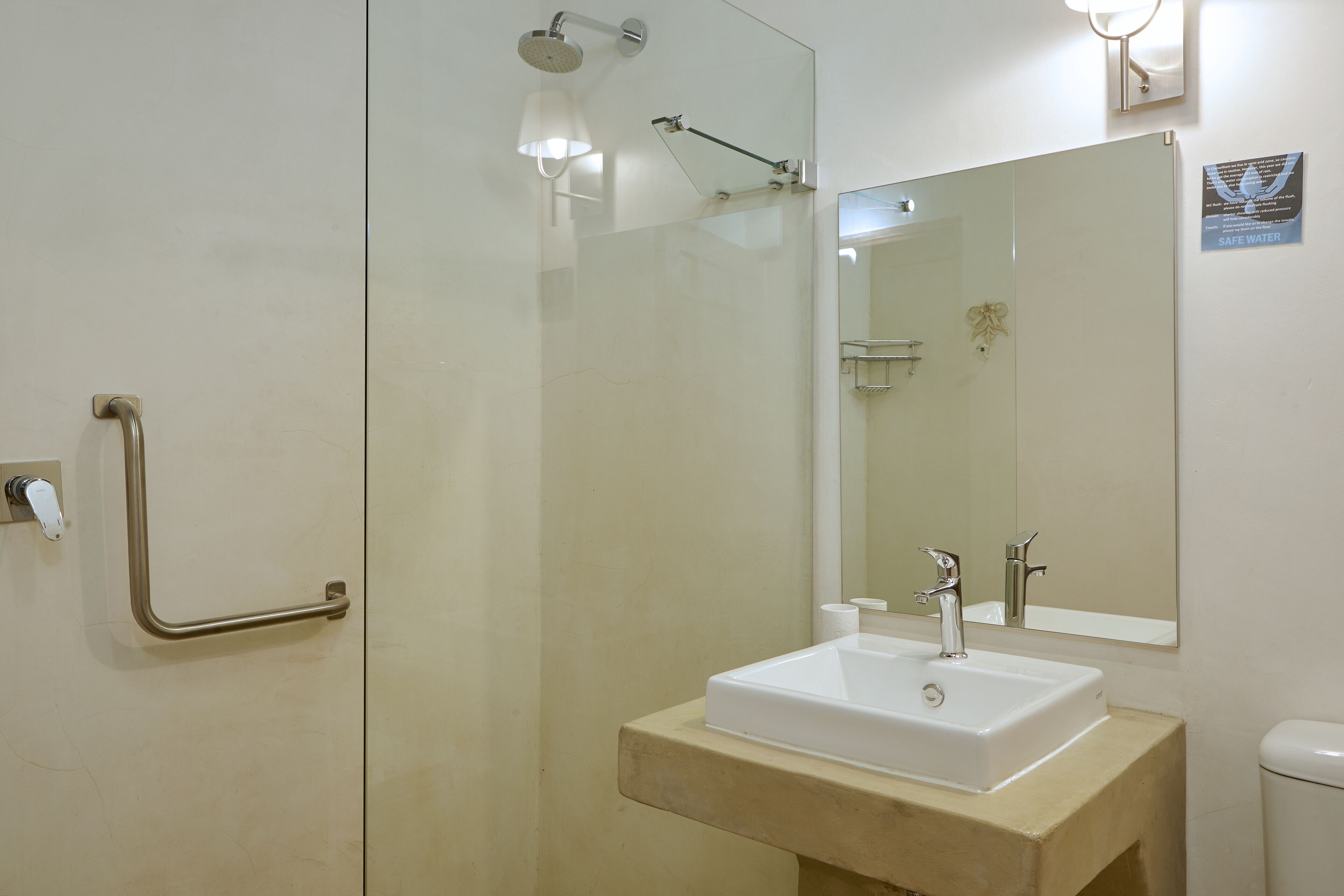 A bathroom with a glass shower enclosure, a sink with a mirror, and a toilet.