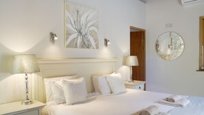 A hotel room with a large bed, two bedside tables, a wall-mounted mirror, and a painting. - Yellow Aloe Guesthouse (Cederberg)