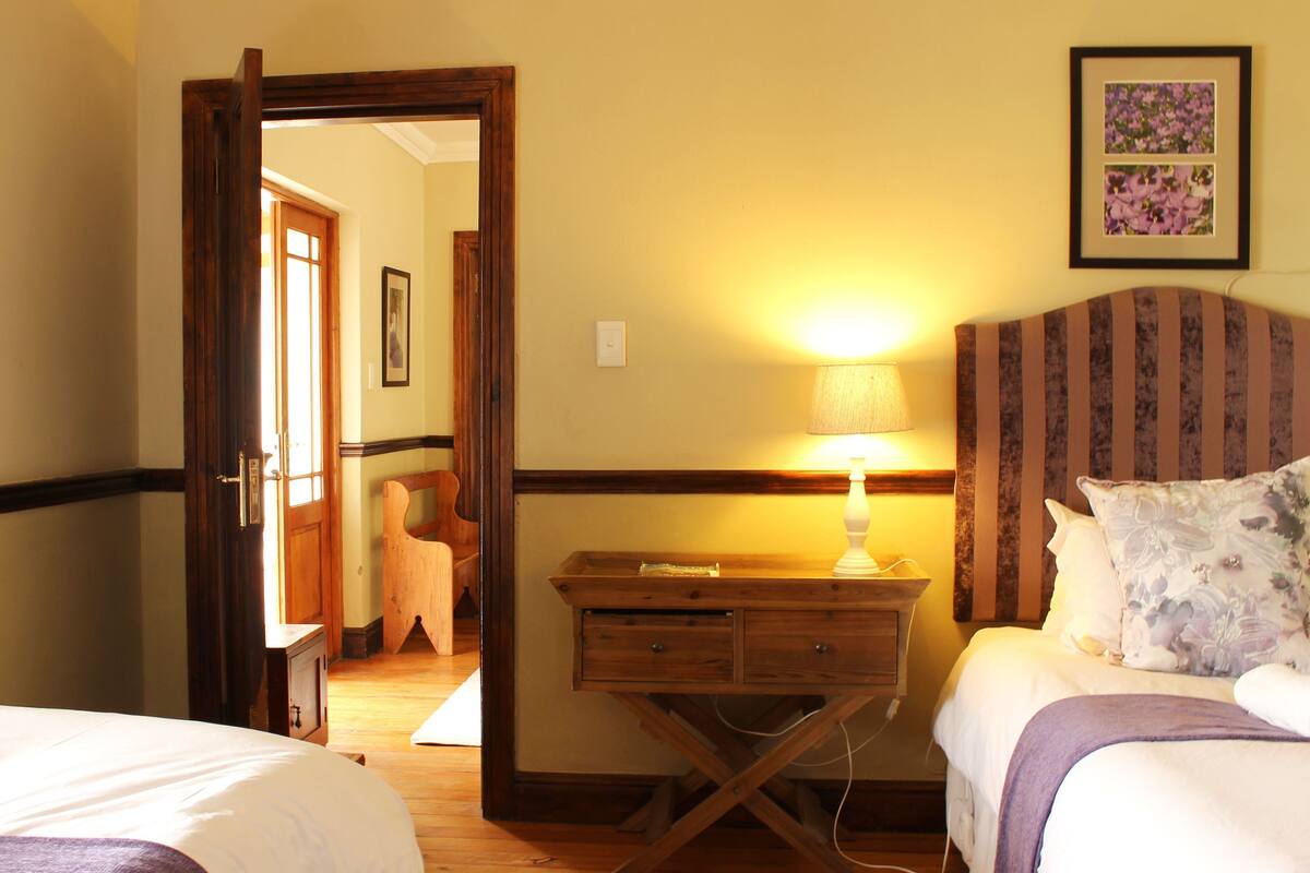 Una habitación de hotel con una cama, una mesita de noche, una lámpara, un aparador y un espejo.