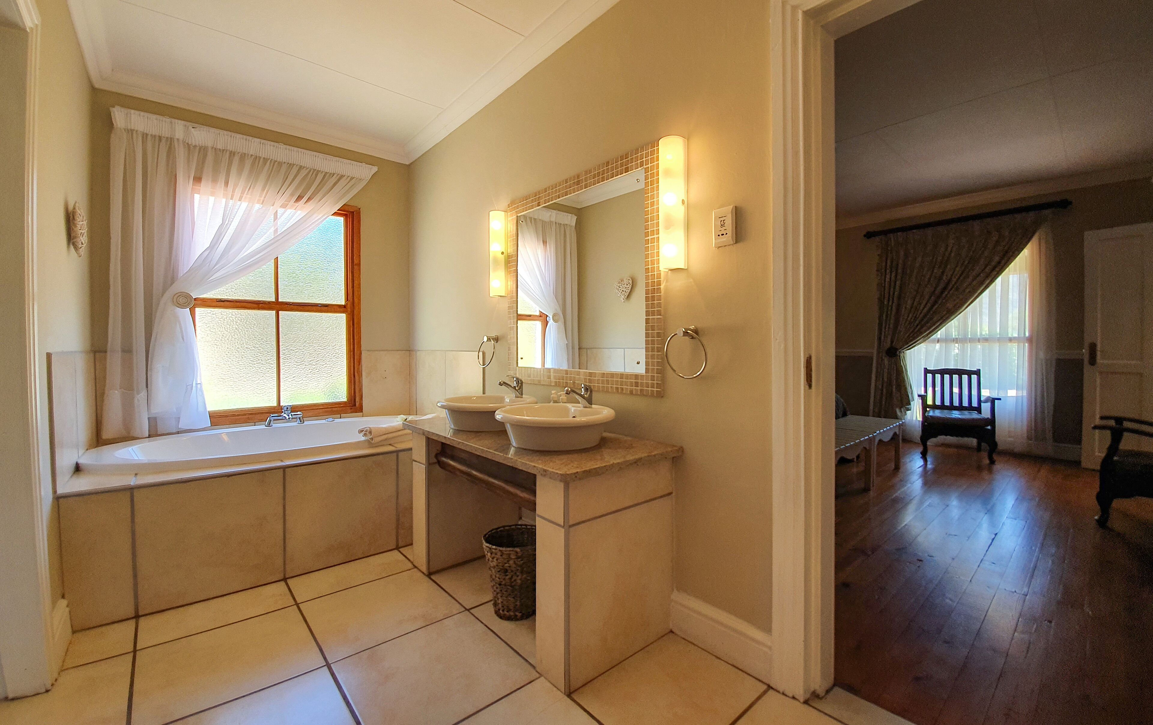 A bathroom with two sinks, a bathtub, and a large mirror.
