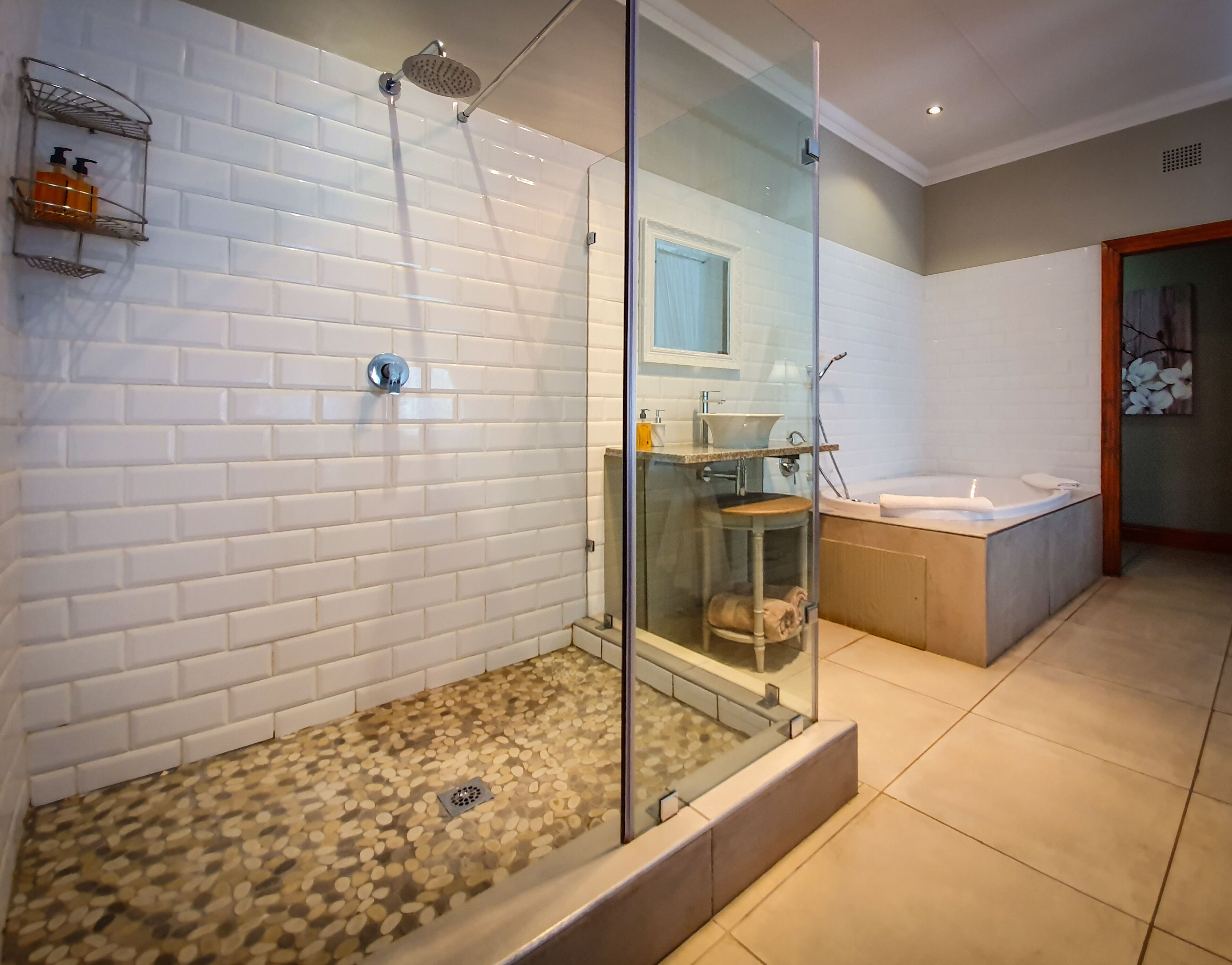 Un baño moderno con ducha envuelta en vidrio, bañera y lavamanos.