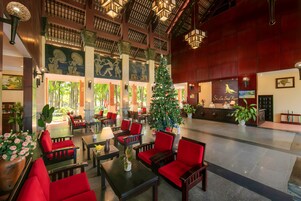 Una hall con sedie rosse, un albero di Natale e una reception.
