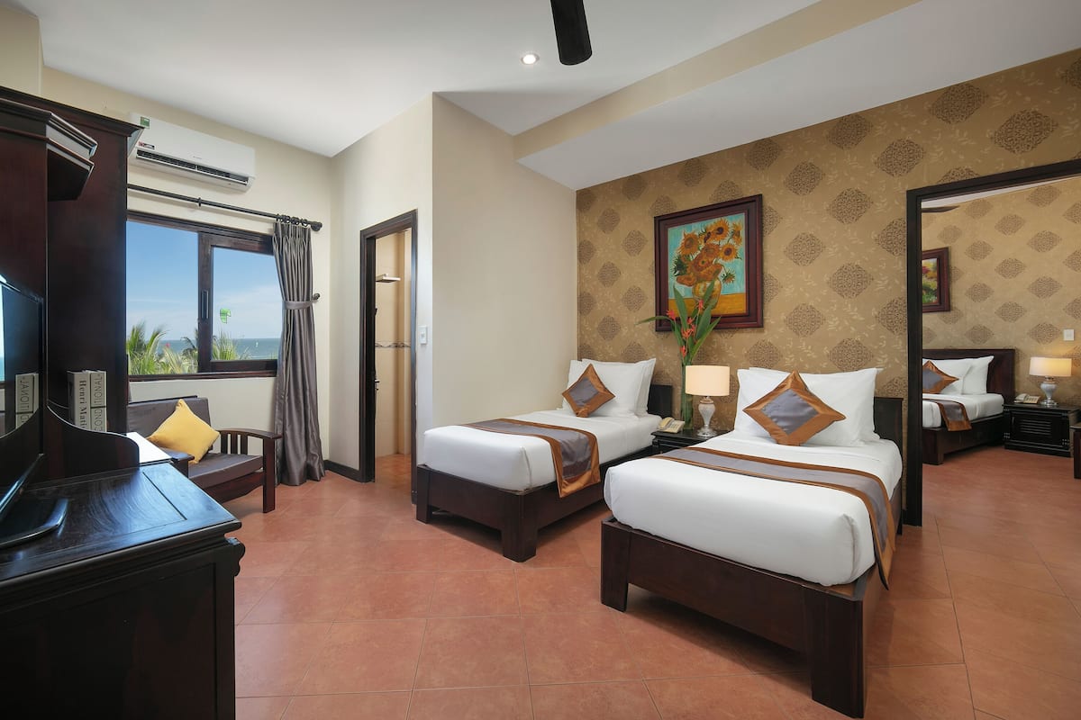 Habitación de hotel con dos camas, televisión y un ventanal con vistas.