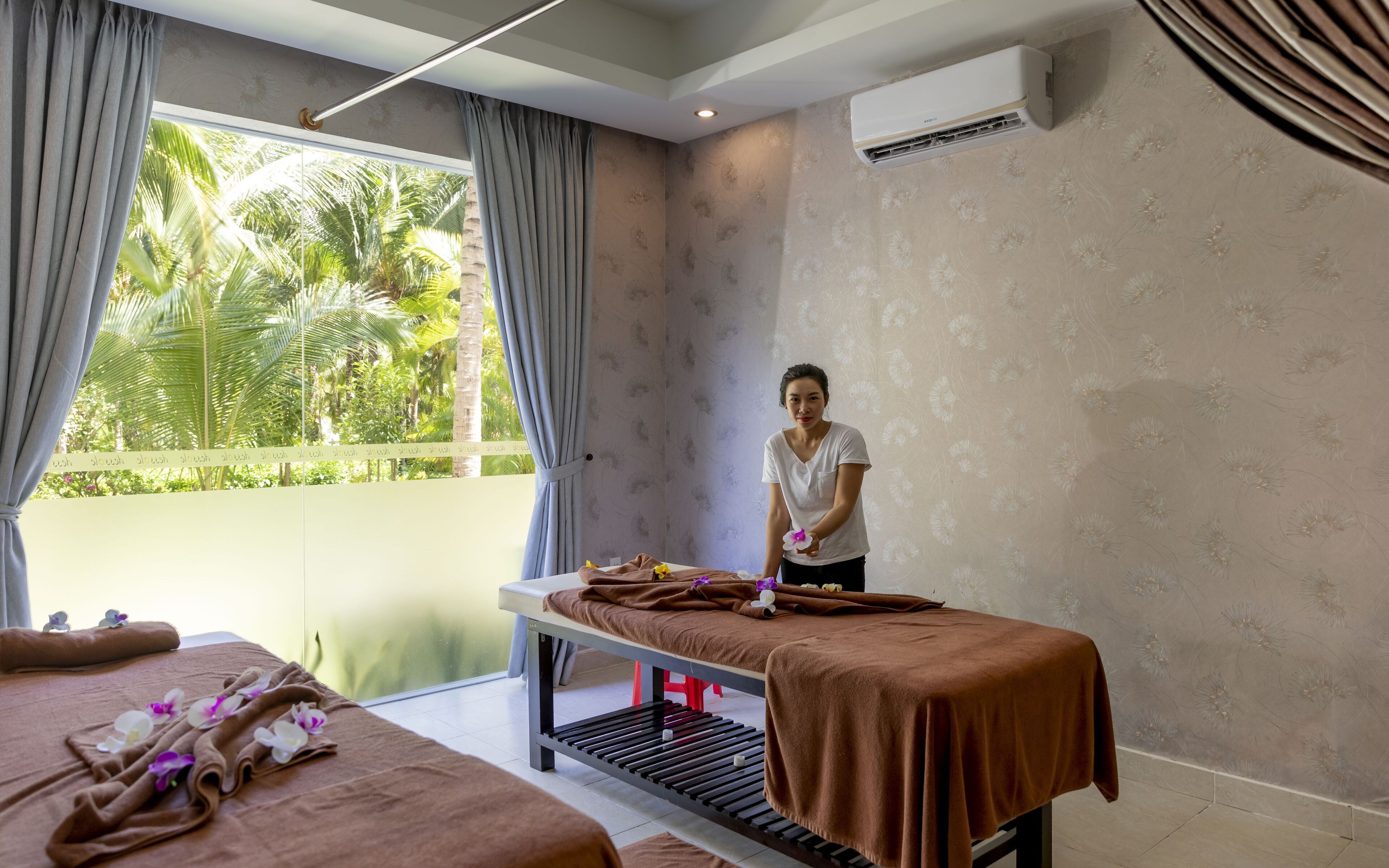 A massage room with a massage table, towels, and flowers.