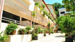 A modern hotel with multiple balconies, potted plants, and a clear sky. - Karon Village Hotel (Karon)