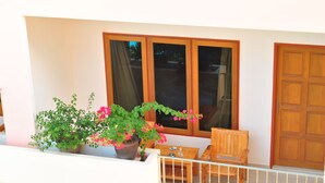 A balcony with potted plants, a wooden bench, and a table. - Karon Village Hotel (Karon)