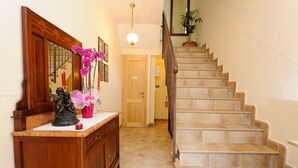 A staircase with a wooden handrail and beige tiles, leading to a door with a sign above it. - Agriturismo Casa Brunori (Foligno)