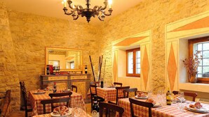 A restaurant with stone walls, checkered tablecloths, and wooden chairs. - Agriturismo Casa Brunori (Foligno)