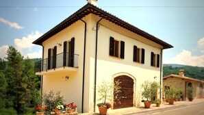 A two-story building with a balcony, a wooden door, and potted plants. - Agriturismo Casa Brunori (Foligno)