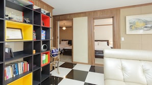 A hotel room with a checkered floor, a bookshelf with various items, a globe on a stand, and a bed with a headboard. - Big John's Place (Seoul)