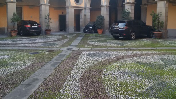 A courtyard with a paved area, potted plants, and parked cars. - Antica Dimora B&B in Historic Residence (Bergamo)
