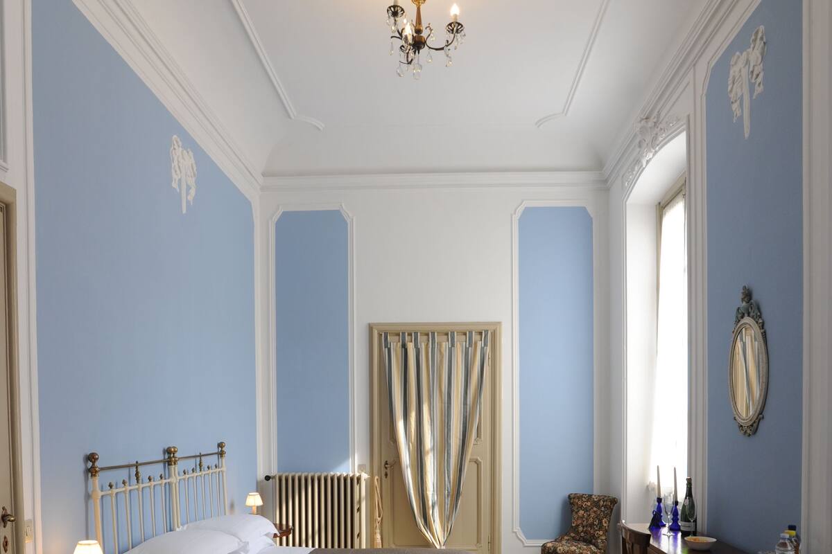 Een slaapkamer met een groot bed, een stoel, een tafel en een kroonluchter.