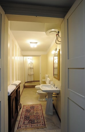 A narrow hallway leading to a bathroom with a sink, toilet, and a towel rack. - Antica Dimora B&B in Historic Residence (Bergamo)