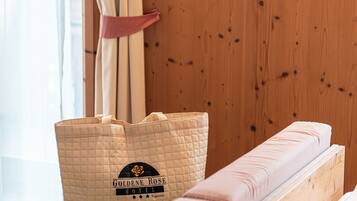 Habitación de hotel con pared de madera, cama con ropa de cama rosa y un bolso acolchado con el logotipo del hotel.