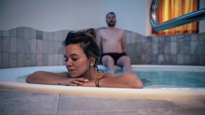 A person in a hot tub with tiled walls and a metal railing. - Hotel Goldene Rose (Monguelfo)