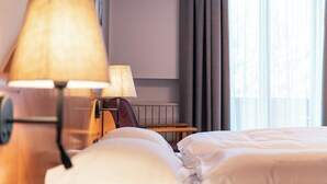 A hotel room with a bed, pillows, a lamp, and a TV on the wall. - Hotel Goldene Rose (Monguelfo)