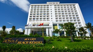 A modern hotel with a large number of balconies, a well-maintained lawn, and a clear blue sky. - Dessole Beach Resort Nha Trang (Cam Lam)