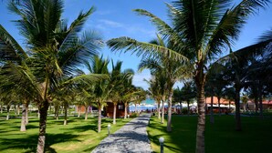A pathway lined with palm trees leading to a building with a red roof. - Dessole Beach Resort Nha Trang (Cam Lam)