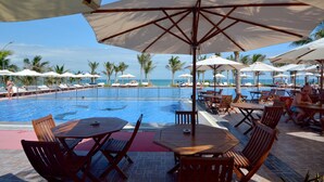 A poolside area with lounge chairs and umbrellas, a pool, and a view of the ocean. - Dessole Beach Resort Nha Trang (Cam Lam)