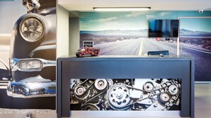 A reception area with a vintage car model, a road scene painting, and a gear mechanism display. - Automobil Hotel (Kraków)