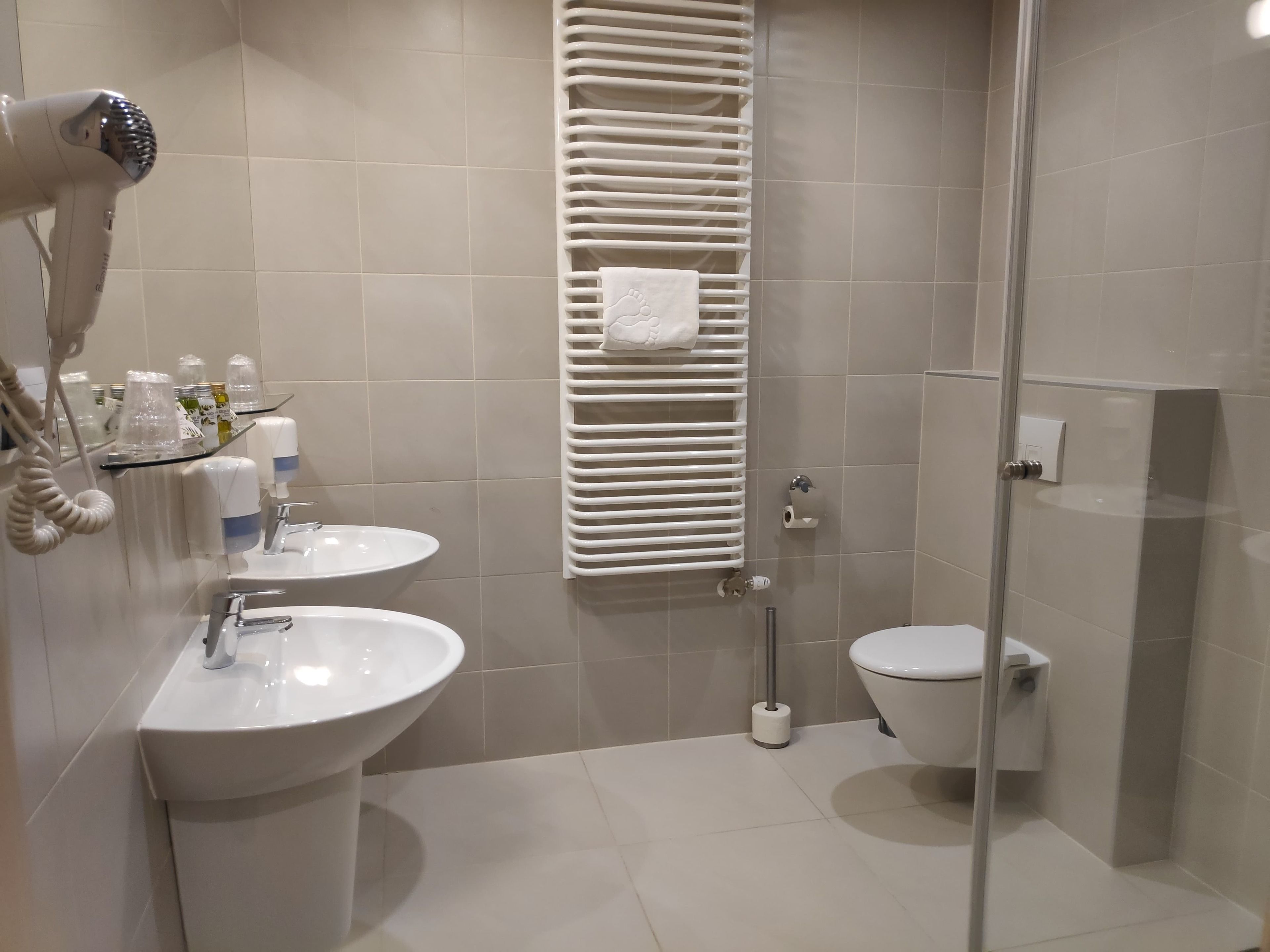 A modern bathroom with a glass-enclosed shower, a white sink, and a toilet.