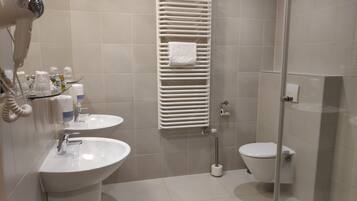 A modern bathroom with a glass-enclosed shower, a white sink, and a toilet.